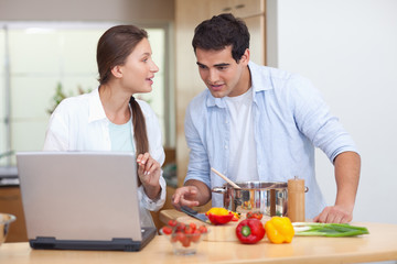 Obraz na płótnie Canvas Couple using a notebook to cook
