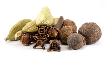 closeup of cloves, cardamon and allspice over white background