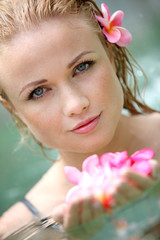 Beautiful woman bathing in pool with frangipani flowers