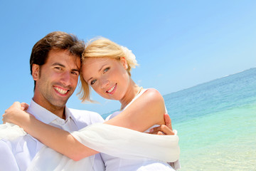 Groom holding bride in his arms by the sea