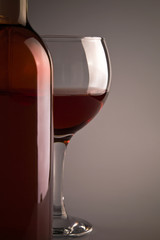 Bottle and glass of wine over grey background