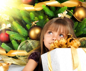 Pretty girl with present near the Cristmas tree
