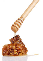tasty honeycombs and wooden drizzler isolated on white