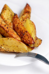 Жаренный картофель на белой тарелке с вилкой