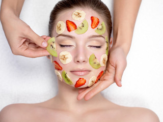 Cosmetician doing fruit mask on a face of  woman - Powered by Adobe