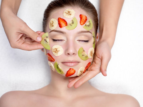 Cosmetician doing fruit mask on a face of  woman