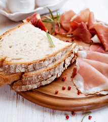 Mediterranean dry cured ham with bread on wooden board