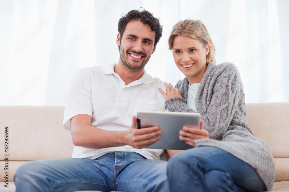Poster Smiling couple using a tablet computer