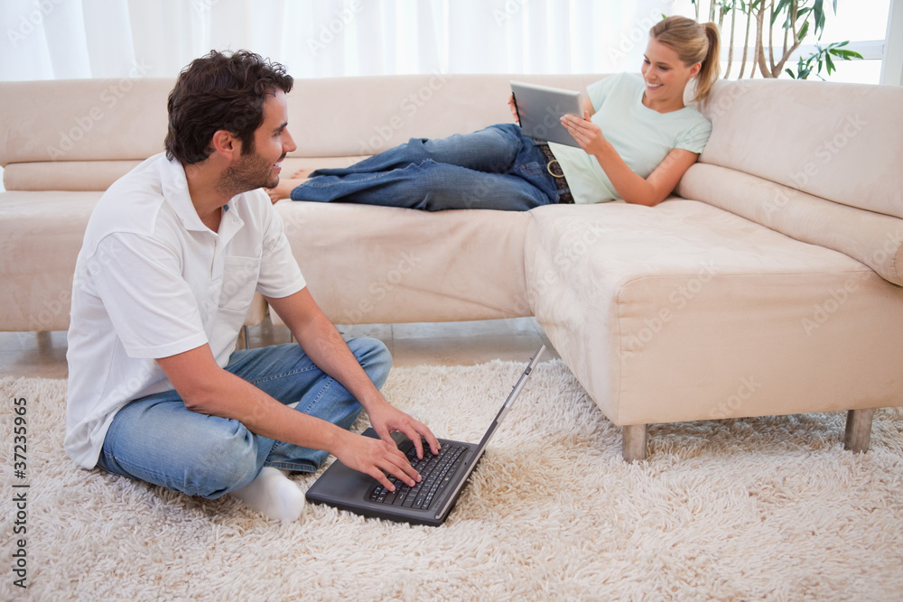Aufkleber woman using a tablet computer while her fiance is using a laptop