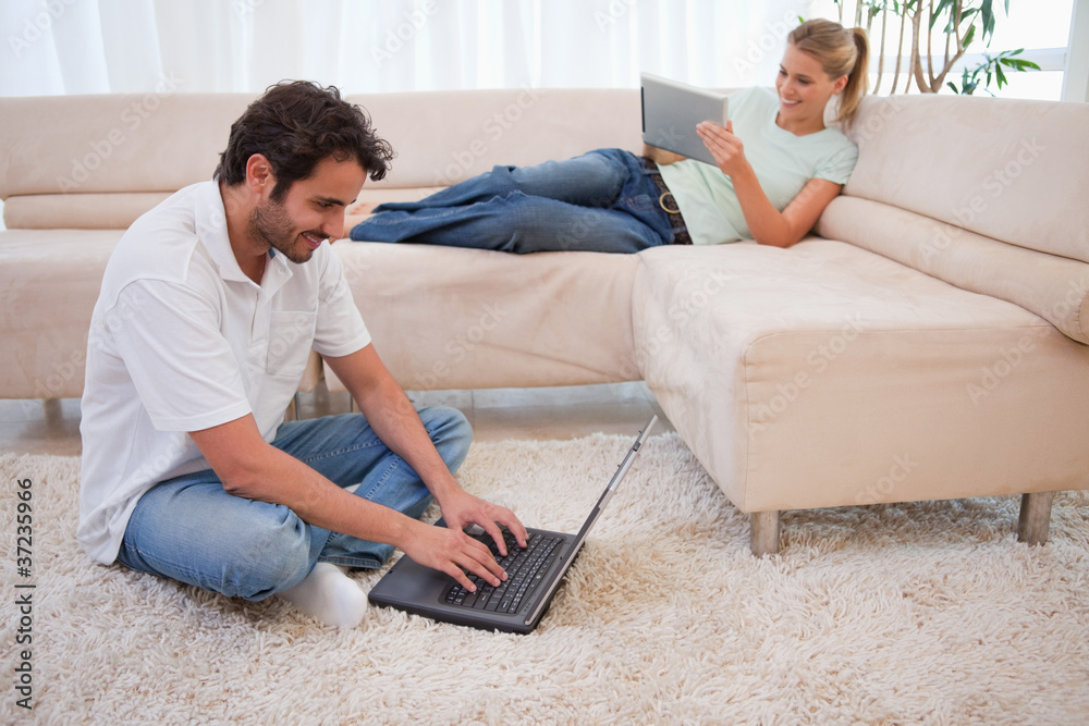 Poster Woman using a tablet computer while her boyfriend is using a lap