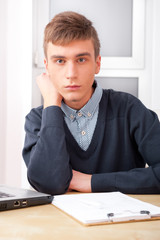 Fototapeta premium Young student man working in bright room, sitting at desk, using
