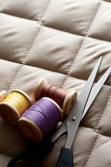 Fototapeta na wymiar Thread bobbins with scissors on a gray fabric
