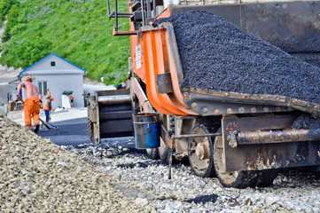 laying asphalt. asphalt paver machine and worker.