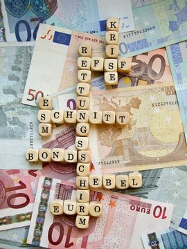 Euro- Krise, W&ouml;rter "Bonds", "Rettungsschirm", "EFSF", "Krise", "ESM", "Bonds", "Euro" und "Schnitt" aus Buchstabenw&uuml;rfeln auf Euro-Scheinen