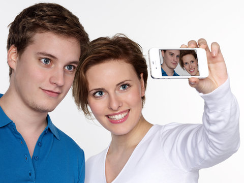 Young couple take a picture of themselves with smartphone