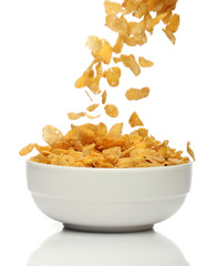 Pouring cornflakes into a bowl, over white background