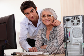 Young man helping an elderly lady use a computer
