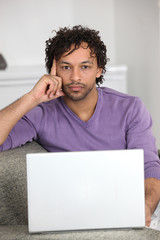 Man using a laptop on his sofa