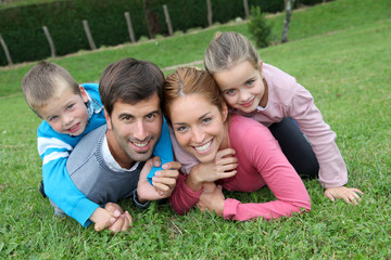 Fototapeta premium Portrait of happy family lying down in grass