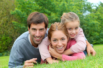 Fototapeta premium Portrait of cheerful family laying on grass