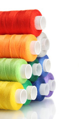 Pyramid of many-coloured bobbins of thread isolated on white
