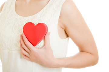 The girl pushes the heart to the chest on a white background.