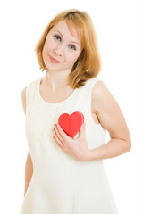The girl pushes the heart to the chest on a white background.
