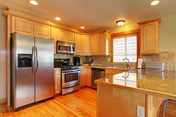 Golden maple cabinets kitchenw with new appliances.