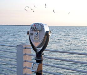 Public beach binoculars on a dock at sunset, Florida.