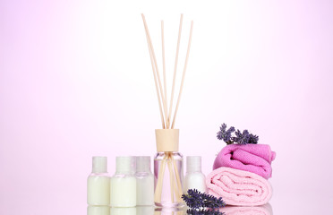 Obraz na płótnie Canvas Bottle of air freshener, lavander and towels on pink background