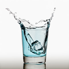 Ice cubes splashing into glass of water