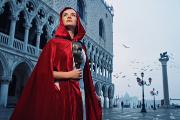 Fototapeta premium Beautiful woman in red cloak against Dodge's Palace