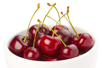 Red ripe cherries in a bowl on white background
