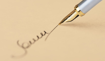 The signature close up and fountain pen. Old yellow paper
