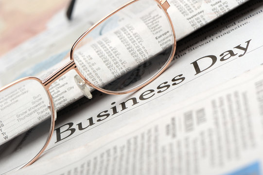 Eyeglasses lie on the newspaper with title Business day