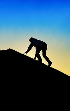 Silhouette of Man Climbing To Top of a Mountain