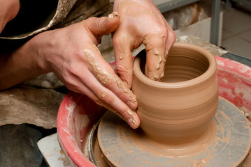 hands of a potter, creating an earthen jar on the circle