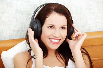 Beautiful woman listening to music through the headphones.