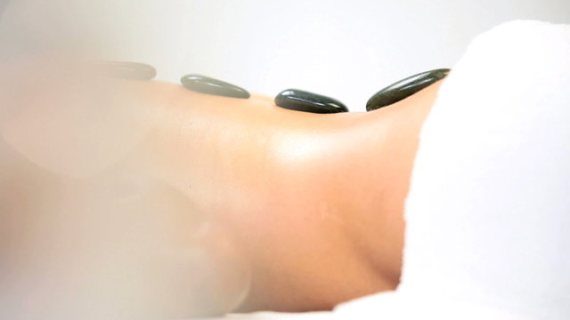 Female Ethnic Spa Client Relaxing with Hot Stone Therapy