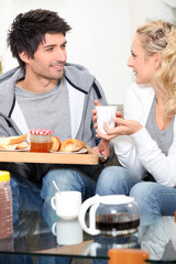 Couple having breakfast together on sofa