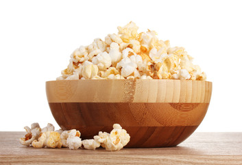 popcorn in wooden bowl on wooden table on white background