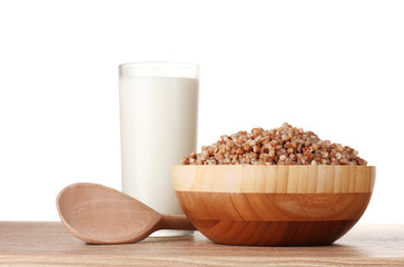 Boiled buckwheat in a wooden bowl with a glass of milk