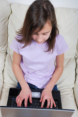Girl sitting on the sofa and using laptop