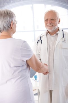 Smiling doctor and patient shaking hands
