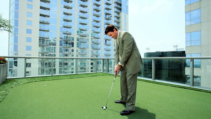 Young Businessman Practicing Golf on City Office Roof - Powered by Adobe