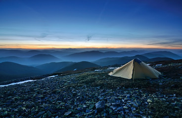 Tourist tent in the rocky mountains and first star