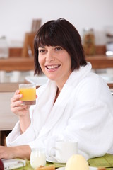 woman in bathrobe having orange juice