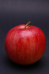 Whole red ripe apple with tail against black
