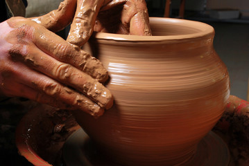 hands of a potter, creating an earthen jar on the circle