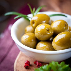 Closeup of pickled green olives in a white dish